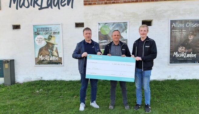 Sol og Strands bureauchef i Lønstrup, Brian Kristensen (til højre) overrække det synlige bevis på sommerhusejernes anerkendelse til Søren og Emil Bendtsen fra MusikLaden.