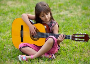 Girl with a guitar in the green grass