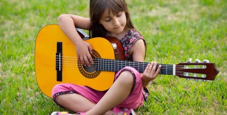 Girl with a guitar in the green grass