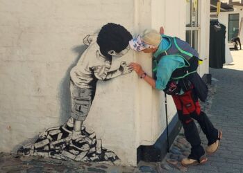 Birthe Nesgaard Johansen fra Vandrefuglens Univers kigger her omkring hjørner efter kunsten i Løkken. Foto: Privat.