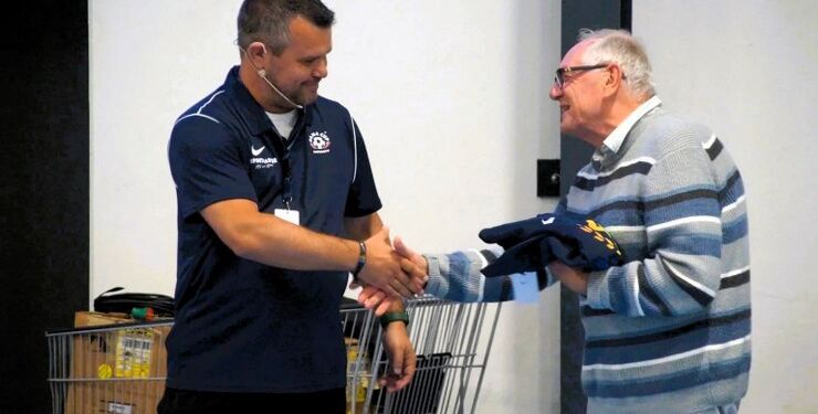 Torsten Wekens hylder her den britiske dommer Bill Hamilton for 25 gange at have stillet sig til rådighed ved Dana Cup. Bill Hamilton fylder 80 i september og dømmer 7:7 kampe ved turneringen. Foto: Dana Cup.