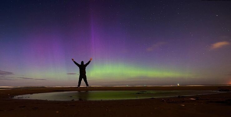 Fotografen jubler i vandkanten over nordlyset ved Hirtshals. Foto: Arturs Pirazkov.