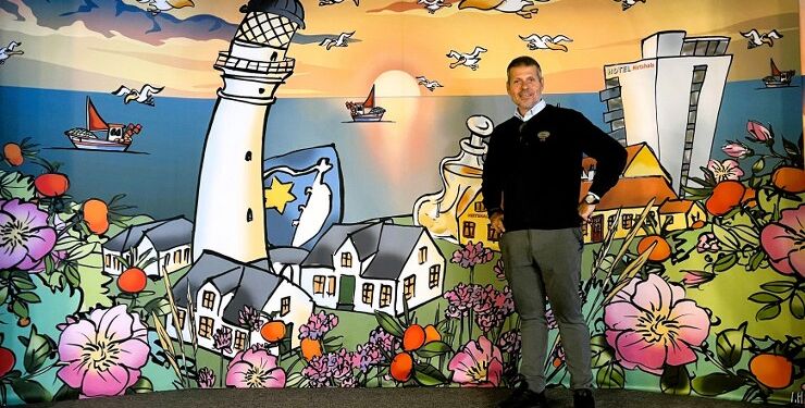 Købmand René Ejstrup Larsen foran det flotte bagtæppe, som han får overdraget efter sidste forestilling hos Hirtshals Revyen. Foto: Niels Skipper.