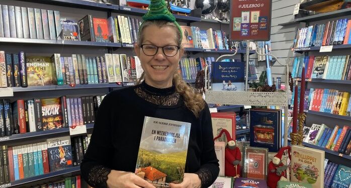 Boghandler Malene Ibsen Jakobsen med den nye bog af René Valdemar Jespersgaard.