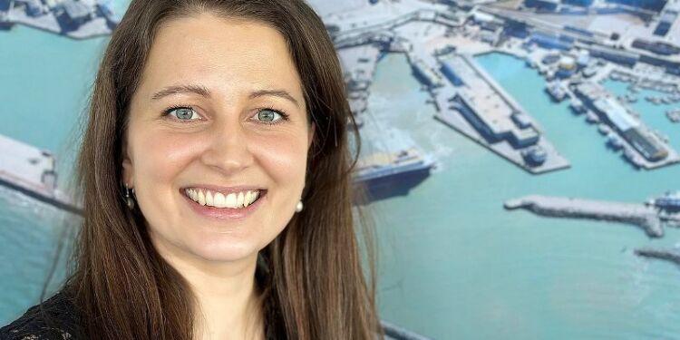 Anja Vrangager foran foto af arbejdspladsen Hirtshals Havn. 
Foto: Henriette Maj Pedersen / TV2 Nord.
