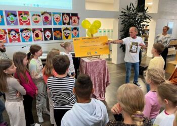 Pædagog Karl Aage Broen afslørede sammen med piger fra 3. klasse det flotte beløb ved morgensang på Bindslev Skole. Foto: Niels Skipper.