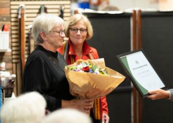 Arne Nielsen overrakte indrammet æresbevis og Joan Mogensen blomster i et stærkt øjeblik, hvor alle til modeshowet hos Dansk Folkehjælp rejste sig og klappede. Privatfoto