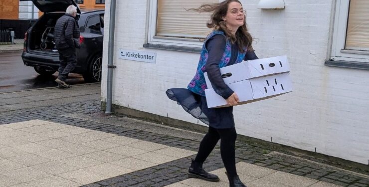 Sognepræst Sofie Boe Lystlund slæber på de tunge kasser med fødevarer fra Over Ugilt Gårdbutik.