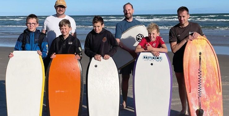 Billedet viser de konfirmander, der var med til sognepræst Johan Hermann Rumps ”sensommer surf-start” på stranden og i det lave vand ved Tversted Strand. Forældre bakkede flot op, og billedet skyldes Tversted-Graverne 2025 (GHS).