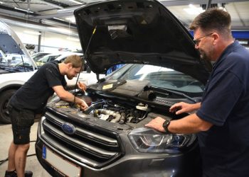 Rasmus i gang med at tilse en bil på værkstedet, mens filialchefen Thomas trygt kigger med. Foto: Mads Laursen