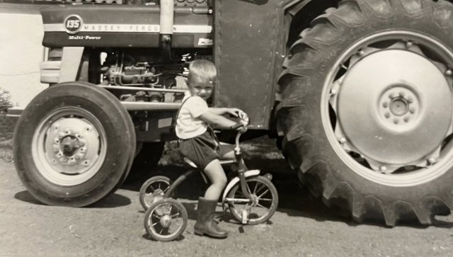 Søren på sin trehjulede cykel foran farens nye Massey Ferguson 135. Foto: Privat.