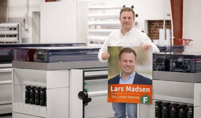 Indehaver Kristian Klokkerholm Kristensen med en valgplakat hos Egotag. Foto: Privat.
