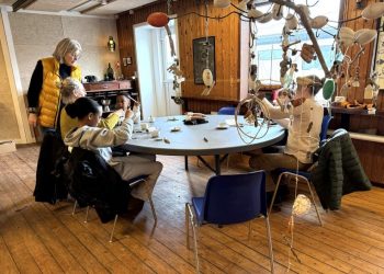 Billedkunstner Laila Pallisgaard giver som arrangør og tovholder en kreativ hånd med i Strandsalen. I forgrunden ses nogle af de mange vindspil ophængt under loftet. Foto: Niels Skipper.