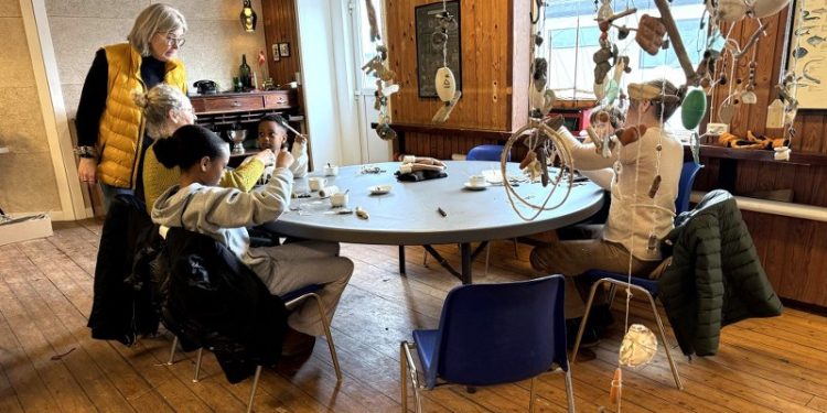 Billedkunstner Laila Pallisgaard giver som arrangør og tovholder en kreativ hånd med i Strandsalen. I forgrunden ses nogle af de mange vindspil ophængt under loftet. Foto: Niels Skipper.