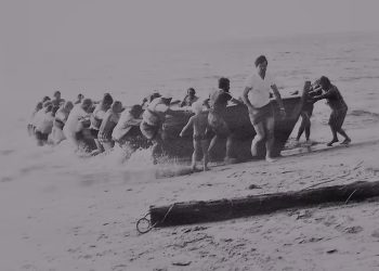 En flok roere haler fladbåden i land på Tornby Strand engang imellem 1970 og 1978. Fotografen ukendt. Foto: Arkiv.dk.