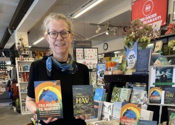 Boghandler Malene Ibsen Jakobsen med to bøger af Kjeld Hansen.