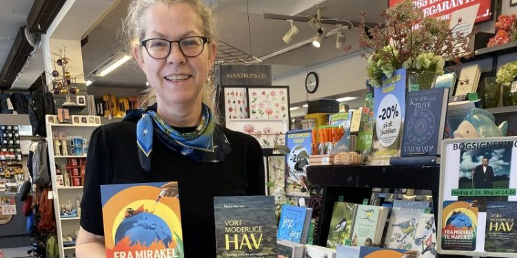 Boghandler Malene Ibsen Jakobsen med to bøger af Kjeld Hansen.