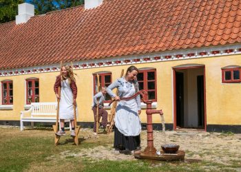 Husmandsfamilien, Ditte Kristiansen og børnene Ella og Lohr, er samlet omkring vandposten. Foto: Niels Helver.