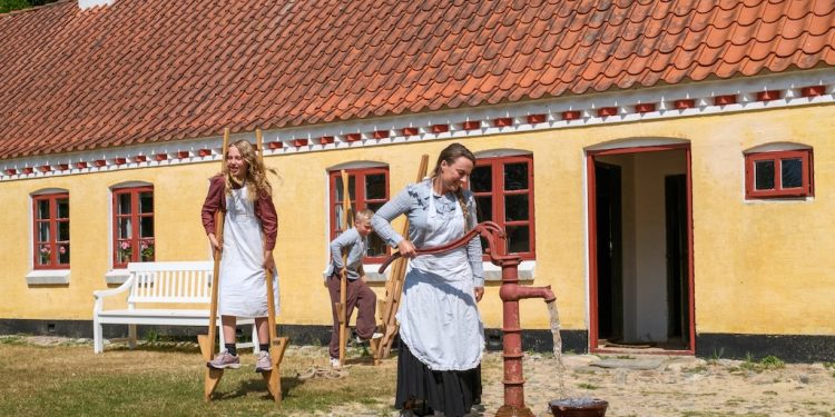 Husmandsfamilien, Ditte Kristiansen og børnene Ella og Lohr, er samlet omkring vandposten. Foto: Niels Helver.
