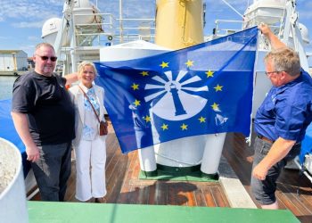 Formand Peter Jensen fra Støtteforeningen Hirtshals Fyr, turistchef Laila Zielke og direktør Espen Frøysland fra Lindesnes Fyrmuseum holder flaget med logoet for European Route of Lighthouses. Foto: Niels Skipper.